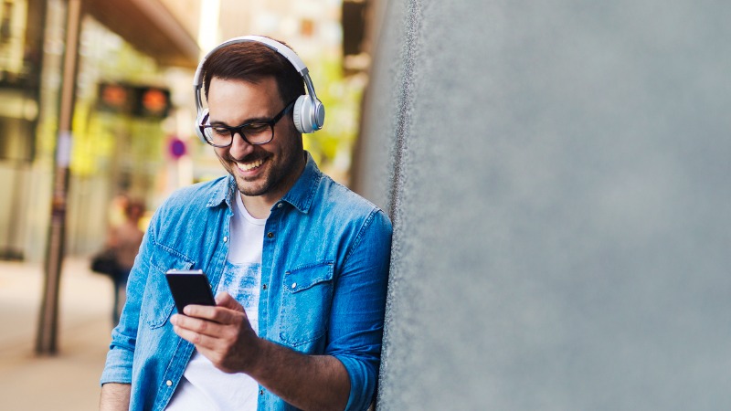 lachende man met draadloze hoofdtelefoon en smartphone